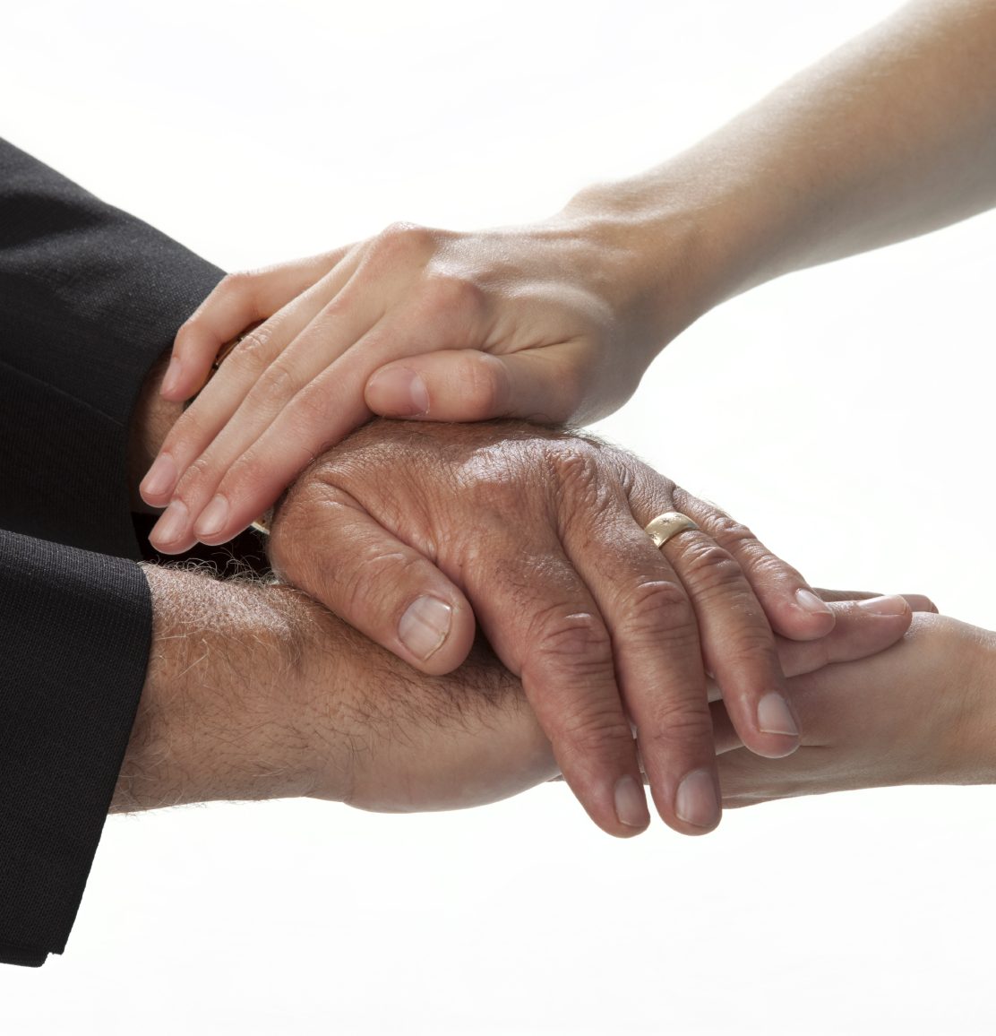 Multiple hands of different ages and skin tones stacked together in a supportive gesture.